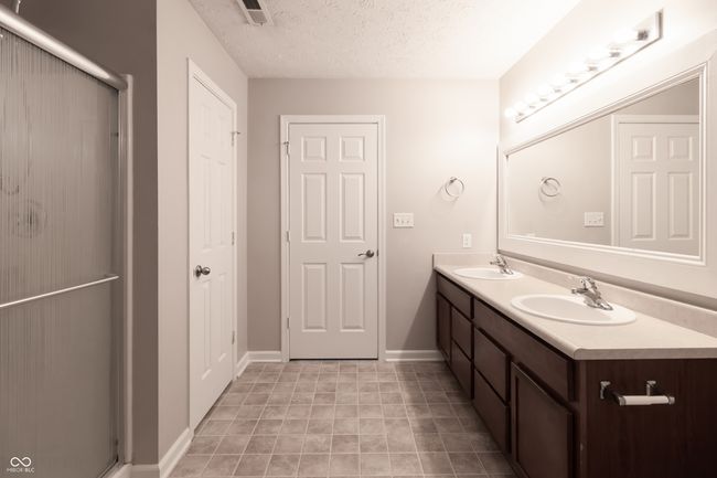 full bathroom featuring double vanity, a stall shower, and a textured ceiling | Image 18
