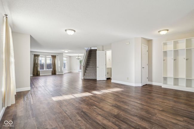unfurnished living room featuring stairway, baseboards, dark wood-style flooring, and built in features | Image 14