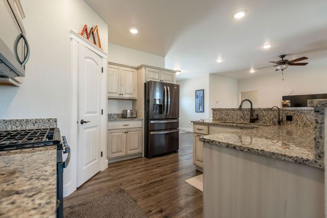 Kitchen featuring stainless steel appliances, ceiling fan, dark wood-style flooring, light stone counters, and recessed lighting | Image 10