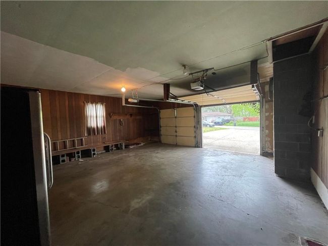Garage featuring a garage door opener, wooden walls, and freestanding refrigerator | Image 37