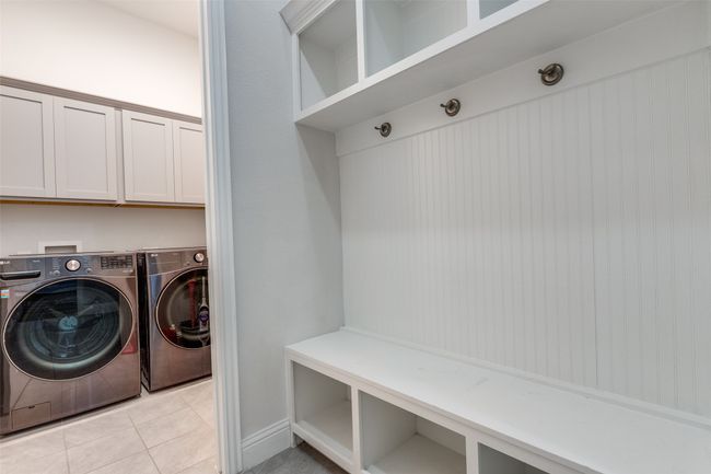 Washroom with light tile patterned floors, cabinet space, and washer and clothes dryer | Image 18