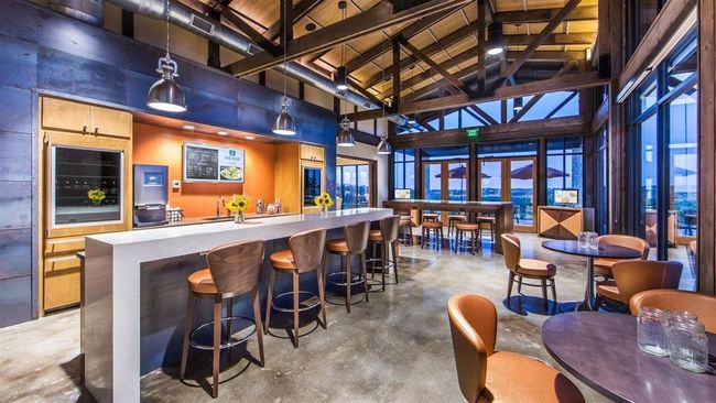 Community bar area with high vaulted ceiling, beverage cooler, concrete floors, a wood ceiling with exposed beams, and hanging light fixtures | Image 19