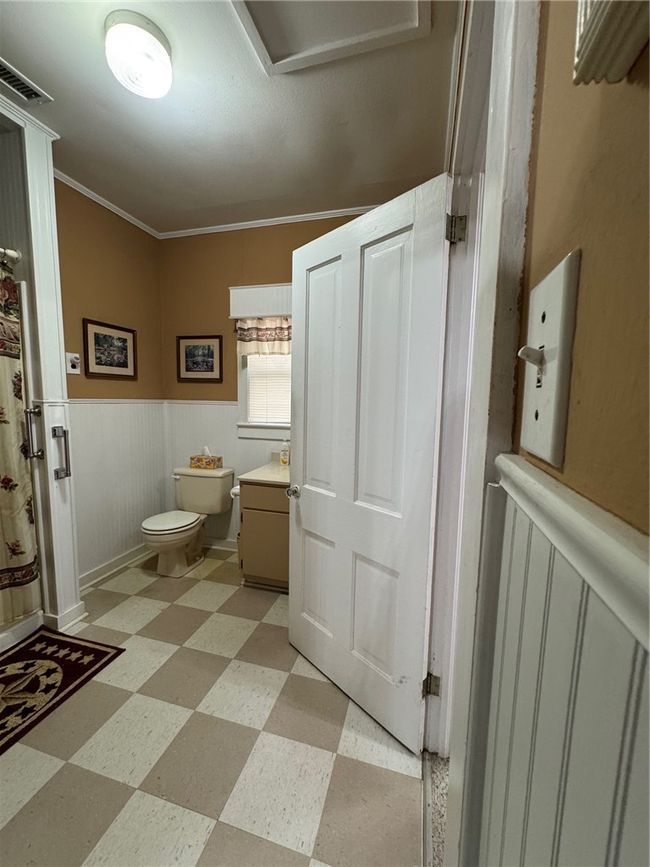 Bathroom featuring tile patterned floors, vanity, wainscoting, and crown molding | Image 17