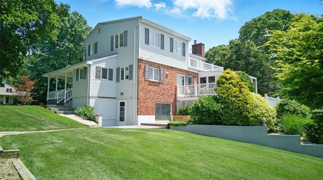 Rear view of house featuring a lawn, a chimney, a balcony, and brick siding | Image 11