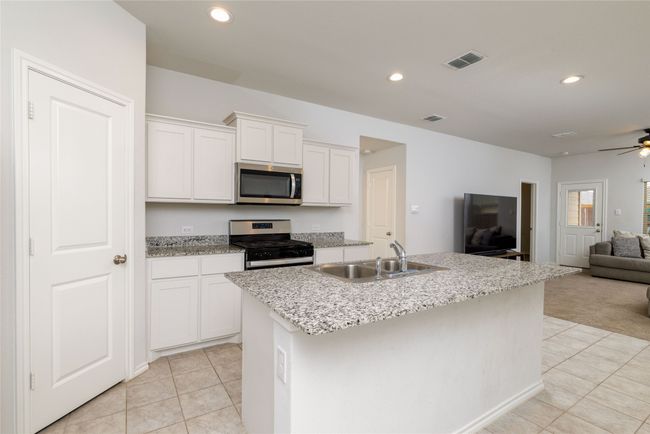 Kitchen with stainless steel appliances, a sink, open floor plan, light tile patterned floors, and ceiling fan | Image 11