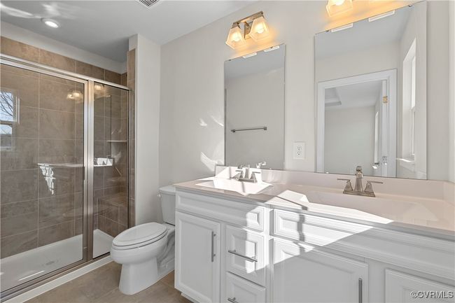 Full bath with a sink, double vanity, toilet, and a stall shower | Image 22
