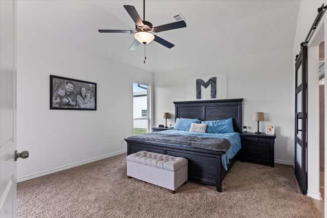Carpeted bedroom with visible vents, baseboards, ceiling fan, and a barn door | Image 20