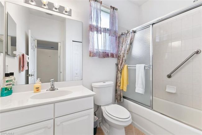 Full bathroom featuring tile flooring, toilet, bath / shower combo with glass door, and large vanity | Image 26