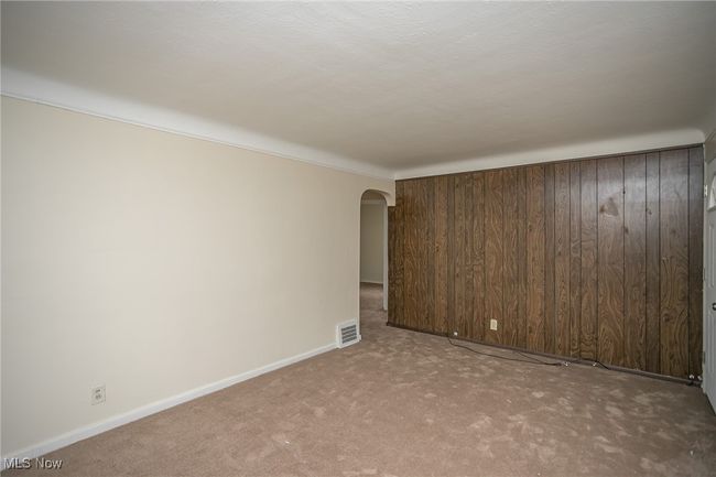 Carpeted spare room with arched walkways and wooden walls | Image 10