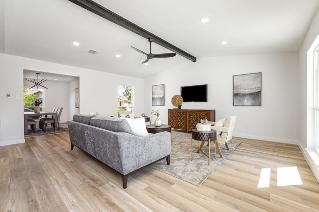 Living room with visible vents, light wood-type flooring, lofted ceiling with beams, and ceiling fan with notable chandelier | Image 15