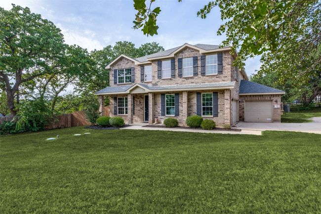 Traditional-style house featuring an attached garage, concrete driveway, roof with shingles, and brick siding | Image 29