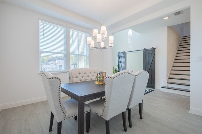 The formal dining room features a lovely overhead light fixture and tray ceilings. | Image 7