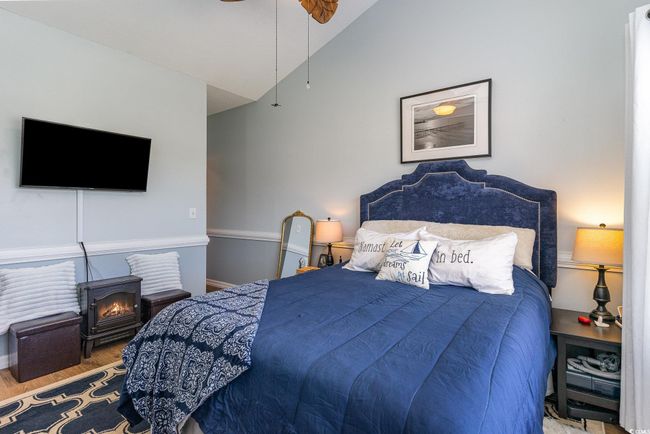Bedroom with vaulted ceiling, wood finished floors, baseboards, and ceiling fan | Image 11