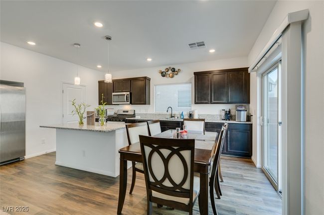 Kitchen with visible vents, wood finished floors, dark brown cabinetry, and appliances with stainless steel finishes | Image 10