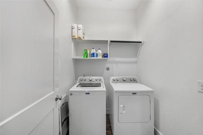 Conveniently located, the laundry room includes shelving for storage and space for full-size appliances, keeping household tasks neat and efficient. | Image 26