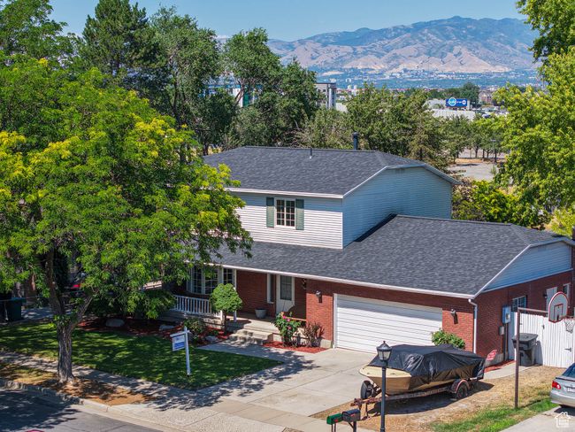 Traditional-style house featuring an attached garage, brick siding, a shingled roof, and a mountain view | Image 21