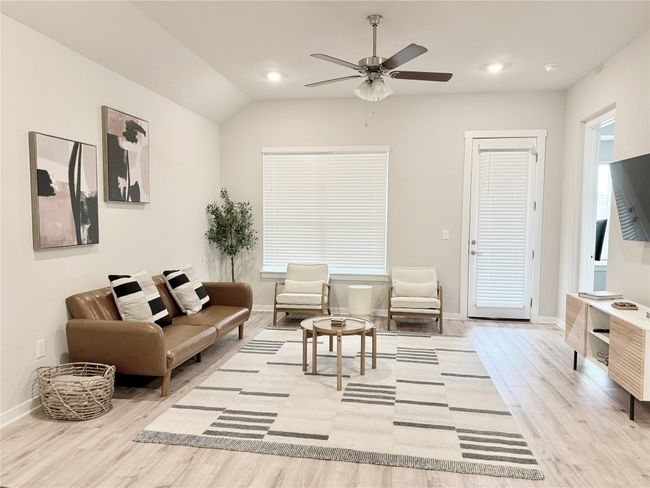 Living area with wood finished floors, baseboards, ceiling fan, lofted ceiling, and recessed lighting | Image 7