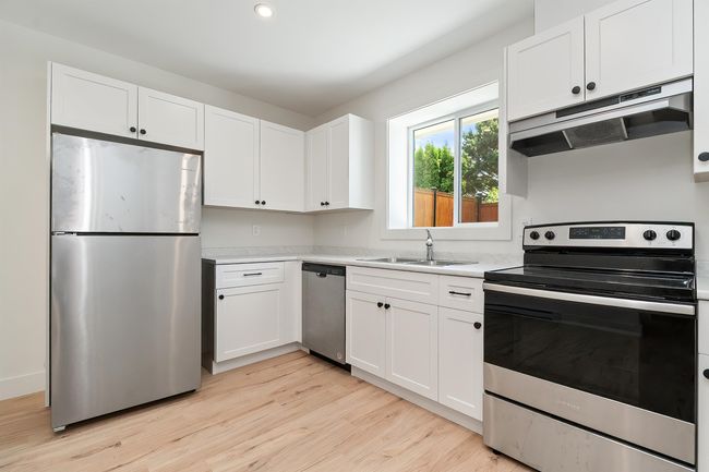 Kitchen with appliances with stainless steel finishes, range hood, white cabinets, and recessed lighting | Image 29