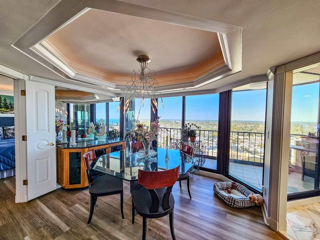 Dining space with a wall of windows, crown molding, a tray ceiling, and a chandelier | Image 15