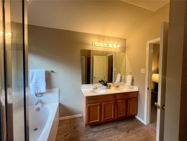 Bathroom with double vanity, a garden tub, vaulted ceiling, and wood finished floors | Image 27