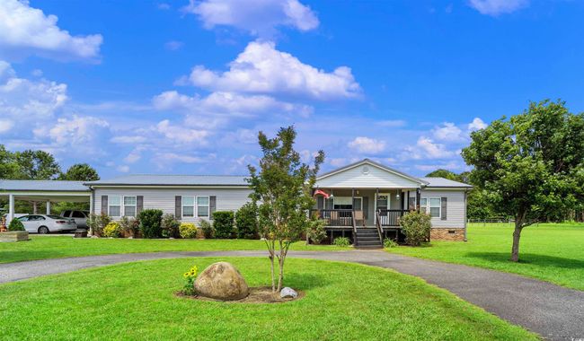 View of front of property featuring a porch, curved driveway, a front yard, a metal roof, and crawl space | Image 17
