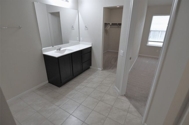 Bathroom featuring baseboards, a walk in closet, tile patterned flooring, and vanity | Image 18