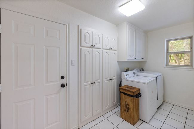 Washroom featuring washing machine and dryer, light tile patterned flooring, and cabinet space | Image 22