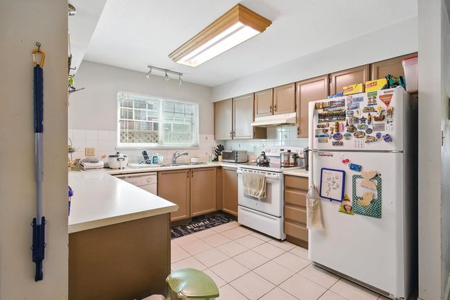 Kitchen featuring white appliances, under cabinet range hood, light countertops, and backsplash | Image 5