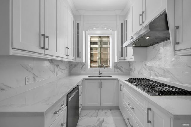 Kitchen featuring under cabinet range hood, appliances with stainless steel finishes, light stone counters, and white cabinetry | Image 12