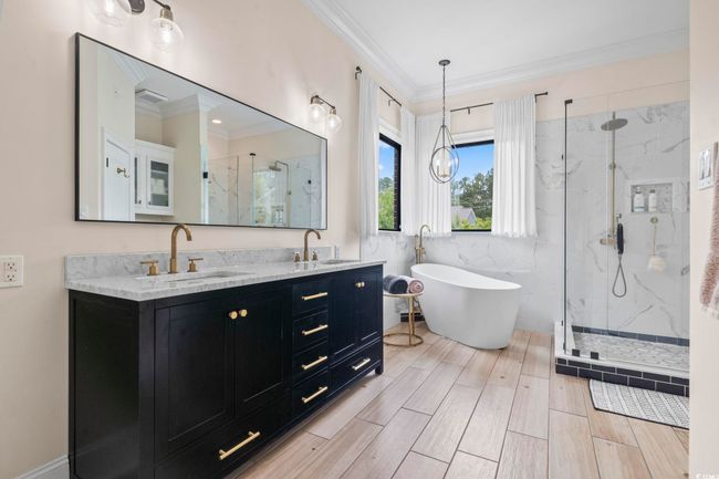 Full bathroom featuring a marble finish shower, double vanity, crown molding, and a freestanding bath | Image 19