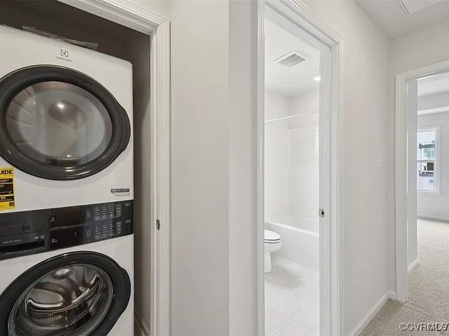 Laundry room with stacked washer / dryer and carpet | Image 23