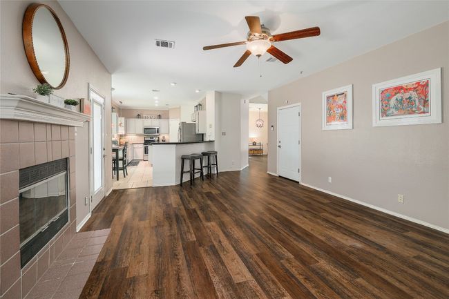 Unfurnished living room featuring visible vents, baseboards, ceiling fan, a fireplace, and wood finished floors | Image 6