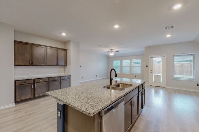 Kitchen featuring stainless steel dishwasher, a sink, visible vents, a ceiling fan, and backsplash | Image 15