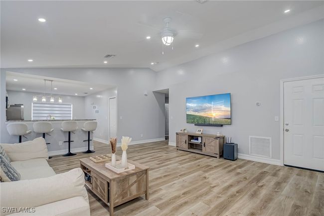 Living room featuring lofted ceiling, light wood finished floors, a ceiling fan, recessed lighting, and baseboards | Image 4