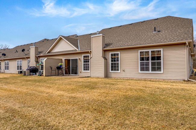 Rear view of the townhouse highlighting the spacious patio, well-kept yard, and attractive exterior design. | Image 35
