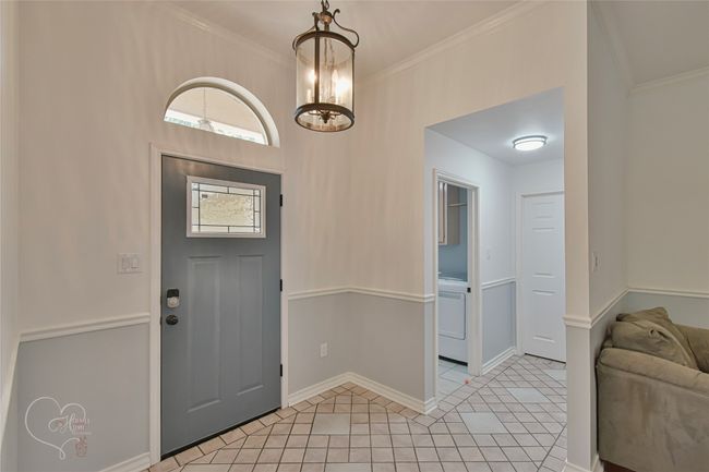 Foyer with light tile patterned floors, ornamental molding, and washer / dryer | Image 37
