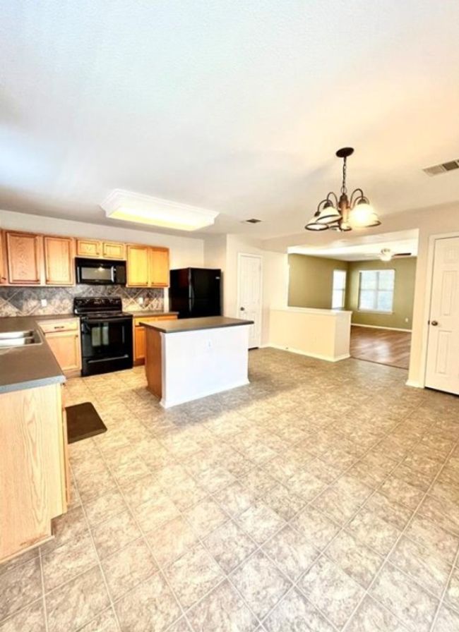 Kitchen with black appliances, a chandelier, decorative backsplash, a center island, and open floor plan | Image 7