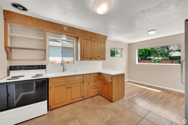 Kitchen featuring range with electric cooktop, a sink, open shelves, a peninsula, and light countertops | Image 7