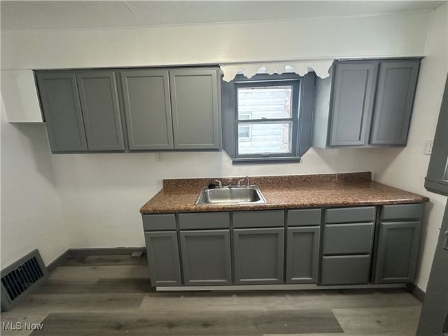 Kitchen with dark countertops, gray cabinetry, a sink, and visible vents | Image 30