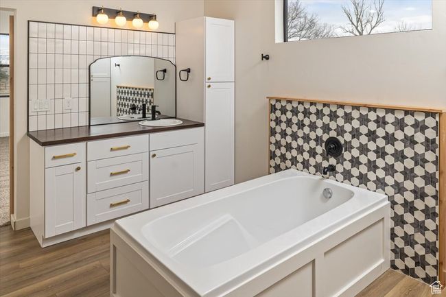 Bathroom featuring hardwood / wood-style flooring, vanity, and a tub to relax in | Image 23