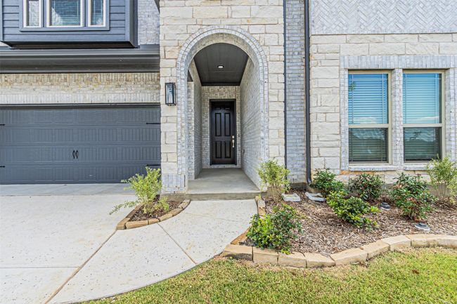 Doorway to property with stone siding, concrete driveway, and brick siding | Image 4