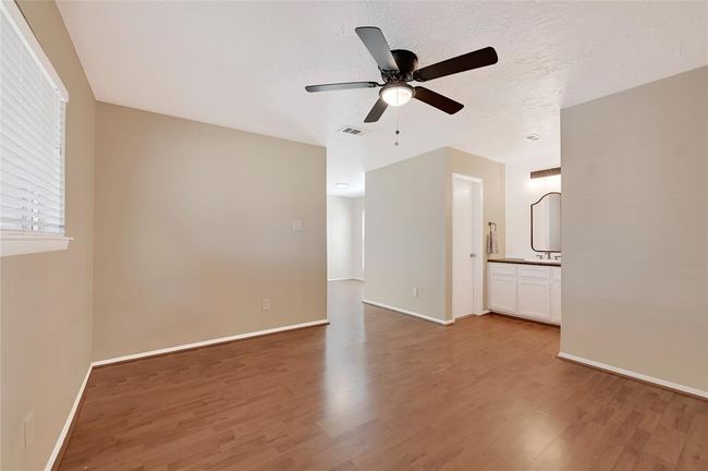 Spacious primary bedroom featuring elegant flooring, a sleek ceiling fan, and a convenient en-suite vanity area. Perfect for relaxation and comfort. | Image 21