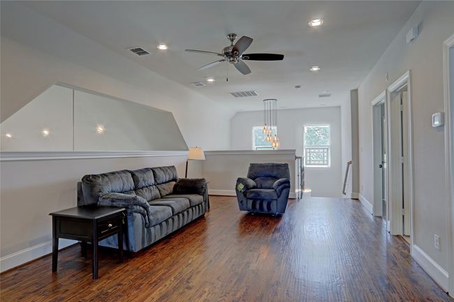 Living area featuring a ceiling fan, dark wood-style floors, and visible vents | Image 23