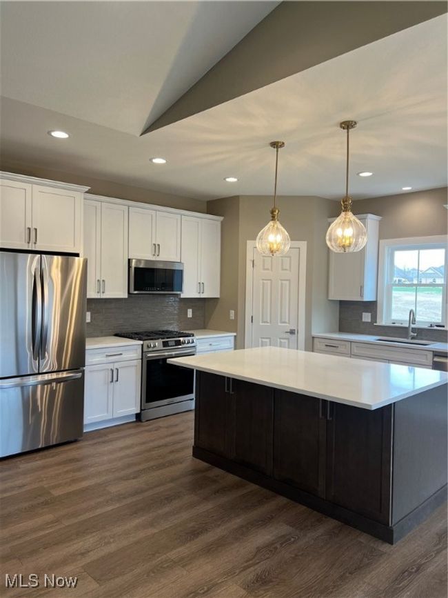 Kitchen with fridge, range, light countertops, white cabinetry, and tasteful backsplash | Image 5