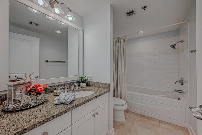 Luxurious master bathroom featuring a shower/tub combo and elegant vanity with ample storage. | Image 12
