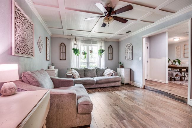Living room featuring coffered ceiling, wood finished floors, ceiling fan, wainscoting, and crown molding | Image 6