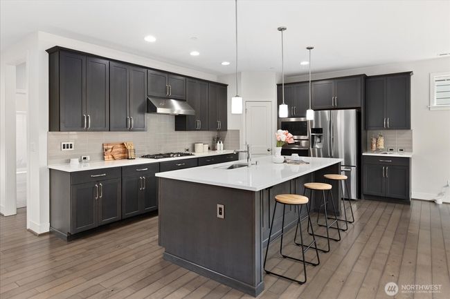 Enjoy the spacious island with seating, sleek cabinetry and quartz countertops | Image 9