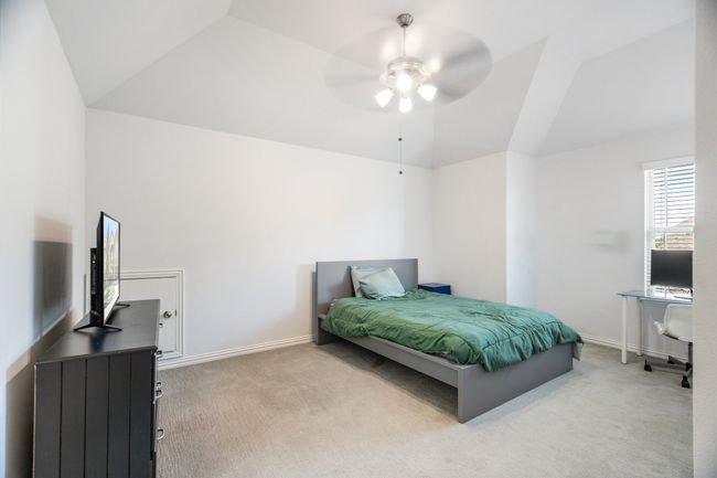 Carpeted bedroom with lofted ceiling, a ceiling fan, and a desk | Image 29