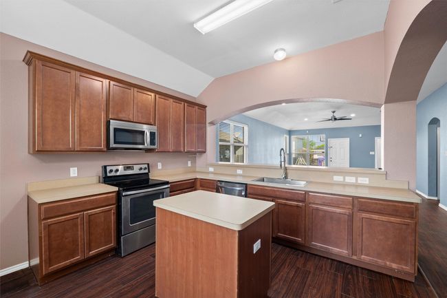 Kitchen featuring arched walkways, a sink, light countertops, appliances with stainless steel finishes, and a ceiling fan | Image 24