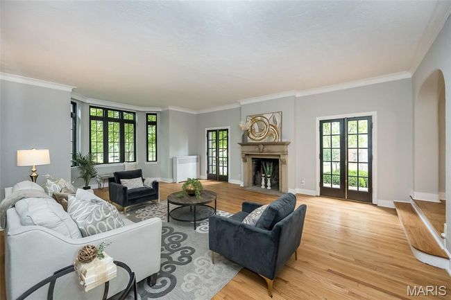 Living room with light wood-style floors, crown molding, and a fireplace with flush hearth | Image 5